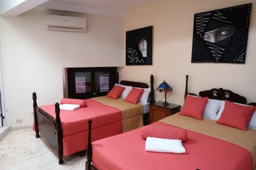 Habitación con 2 camas con cojines rojos en Casa Sayli Appartement 2, en La Habana