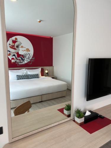 a mirror in a room with a bed and a tv at Hotel Midtown Ratsada in Phuket Town