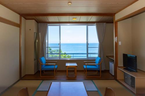 a room with a table and chairs and a large window at Kyukamura Shikanoshima in Fukuoka