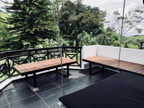 a swing and a bench on a balcony with trees at 80 Colonie Fraser's Hill 16 Pax in Bukit Fraser
