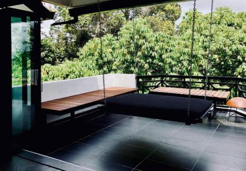 a swinging bench on a porch with trees in the background at 80 Colonie Fraser's Hill 16 Pax in Bukit Fraser