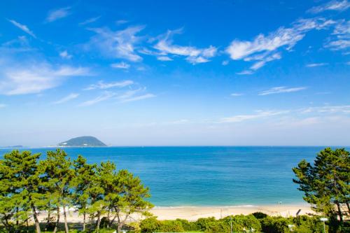 a view of a beach with trees and the ocean at Kyukamura Shikanoshima in Fukuoka