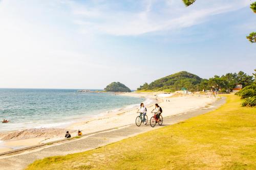two people riding bikes on the beach at Kyukamura Shikanoshima in Fukuoka