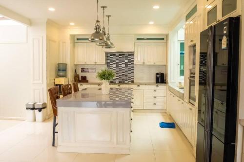 a kitchen with white cabinets and a black refrigerator at 5BD Luxury Pool Villa Pattaya - Exquisite Pool Villa C in Pattaya South