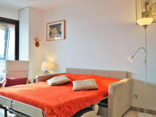 a bedroom with a bed with an orange blanket at Le Lavandou : T2 avec 4 couchages, terrasse, parking en option, animaux admis - FR-1-251-212 in Le Lavandou