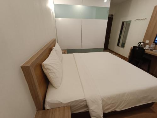 a bedroom with a white bed with a glass door at Greencity Hotel in Sungai Petani