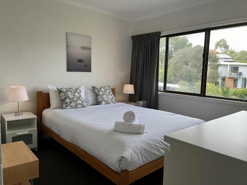 a bedroom with a bed and a large window at Alpine Mountain View 41 in Jindabyne