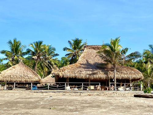 eine Gruppe von Strohhütten am Strand mit Palmen in der Unterkunft Sumba Beach House in Waikabubak