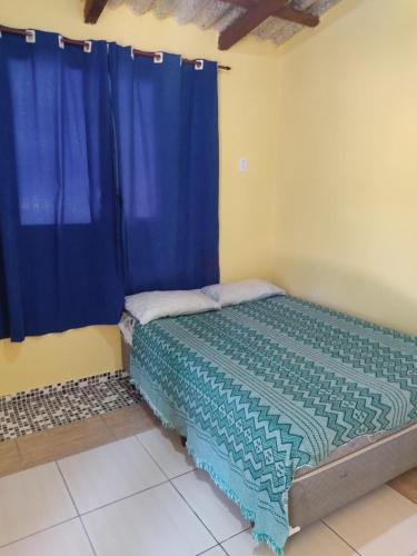 um quarto com uma cama com cortinas azuis em Paraty casa suite em Paraty