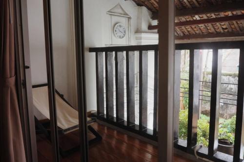 a staircase with a clock on the wall next to a window at Chino Town Gallery Alley - SHA Plus in Phuket Town