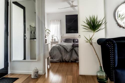 a bedroom with a bed and a mirror at The White Cottage Byron Bay in Suffolk Park