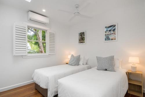 two beds in a room with white walls and a window at Espadrille Tres in Byron Bay