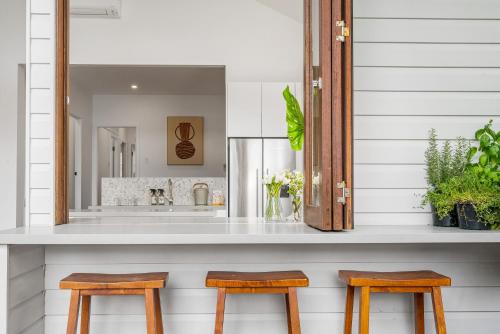 a bathroom with a sink and two wooden stools at Espadrille Tres in Byron Bay