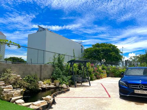a blue car parked in a parking lot at Hotel Phạm Gia Phan Thiết in Phan Thiet