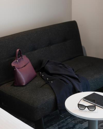 a purse and glasses on a couch with a table at Mercure Sydney Blacktown in Blacktown