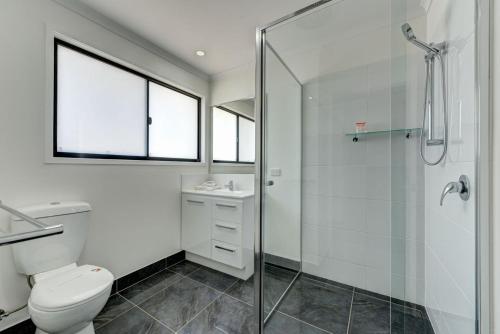 a bathroom with a toilet and a glass shower at Unit 3 Everdell Street in Bargara