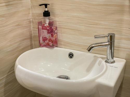 Muni Residence & Spa في باتامبانغ: وجود مغسلة بيضاء في الحمام مع وجود زجاجة من الصابون
