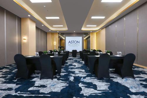 a conference room with tables and chairs and a screen at Aston Mojokerto Hotel & Conference Center in Mojokerto