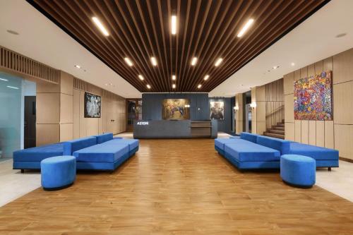 a lobby with blue couches and a stage at Aston Mojokerto Hotel & Conference Center in Mojokerto