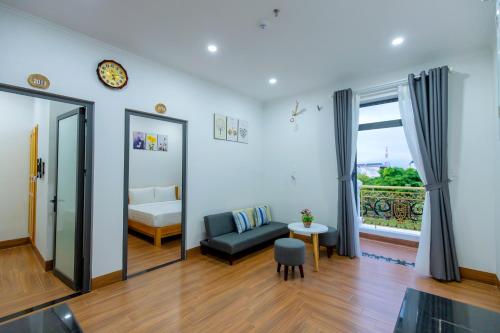 a living room with a couch and a bed and a window at Hotel Phạm Gia Phan Thiết in Phan Thiet