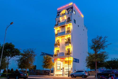 a tall white building with neon lights on it at Hotel Phạm Gia Phan Thiết in Phan Thiet