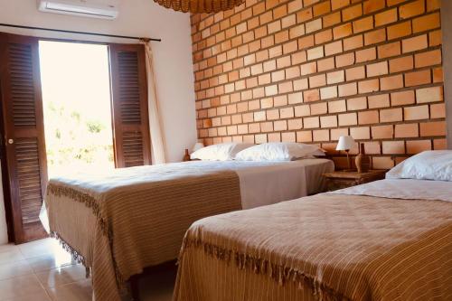 two beds in a room with a brick wall at Casa com piscina aquecida, privativa,diarista, em condomínio, Bonito-Pe in Bonito
