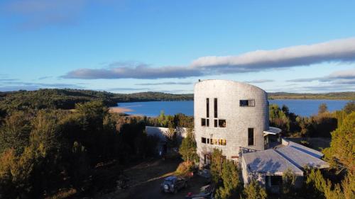 卡斯特羅的住宿－Lodge Parque Tepuhueico，享有湖畔白色大建筑的空中景色