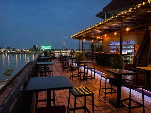 a row of tables and chairs on a patio next to the water at Onederz Hostel Phnom Penh in Phnom Penh