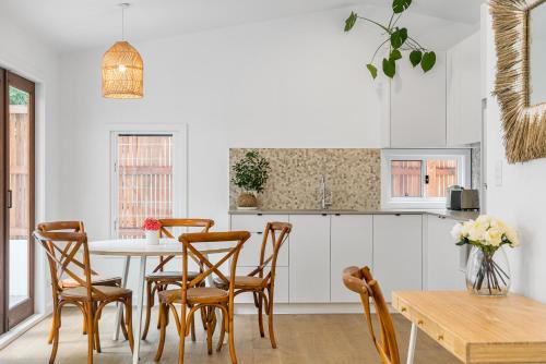 a white kitchen with a table and chairs at Espadrille Casita in Byron Bay