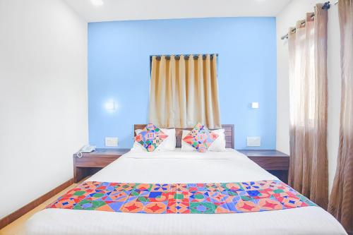 1 dormitorio con 1 cama grande y almohadas coloridas en FabExpress Coco Goa Resort With Pool, Arpora en Saligao