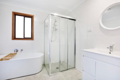 a white bathroom with a tub and a glass shower at Callala Calm Pet Friendly 5 Mins Walk to Beach in Callala Bay