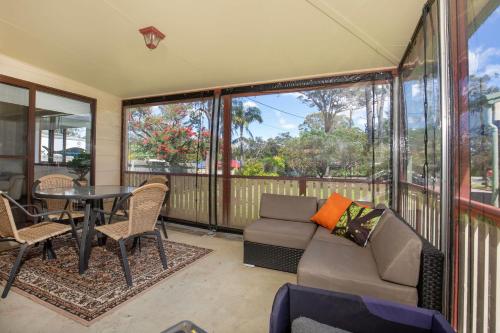 a screened in porch with a couch and a table at Callala Calm Pet Friendly 5 Mins Walk to Beach in Callala Bay