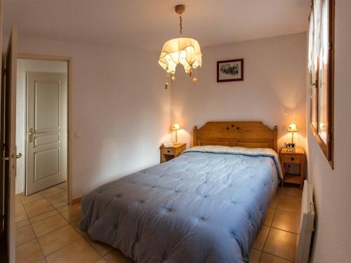 une chambre avec un grand lit et un lustre dans l'établissement Appartement Sud 6 pers avec Terrasse, WiFi, et Parking Optionnel - Animaux Admis - FR-1-393-32, à Saint-Michel-de-Chaillol