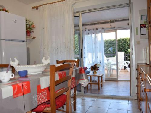 une cuisine avec une table et une porte donnant sur une terrasse. dans l'établissement Appartement Rez-de-Jardin: Piscine, Terrasse, Parking, Wi-Fi en Option - FR-1-387-63, à Marseillan