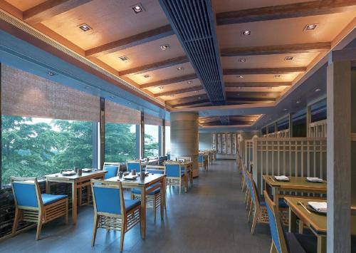 a restaurant with wooden tables and chairs and windows at New World Millennium Hong Kong Hotel in Hong Kong