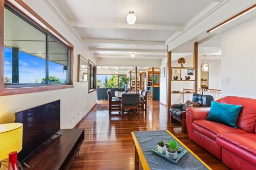 a living room with a red couch and a table at Farrants Hill - Tweed Coast Holidays in Clothiers Creek