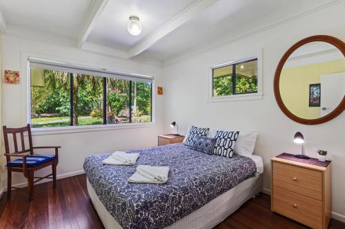 a bedroom with a bed and a chair and a mirror at Farrants Hill - Tweed Coast Holidays in Clothiers Creek