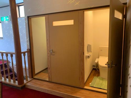 La salle de bains est pourvue de toilettes et d'une porte en verre. dans l'établissement 民宿ニュー万福茶屋, à Taketa