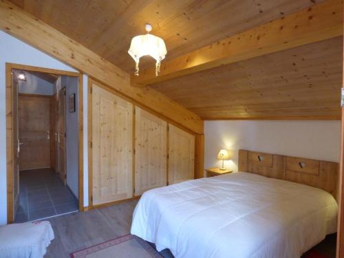 a bedroom with a white bed and wooden walls at Appartement Le Grand-Bornand, 4 pièces, 8 personnes - FR-1-458-147 in Le Grand-Bornand