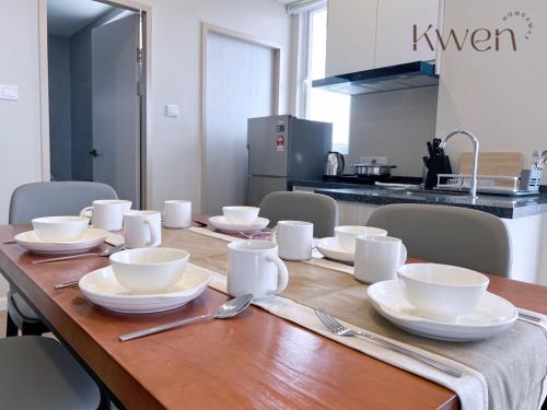 a wooden table with white bowls and plates on it at KWEN Suites-Tanjung Aru InfinityPool Seaview/Airport View in Kota Kinabalu