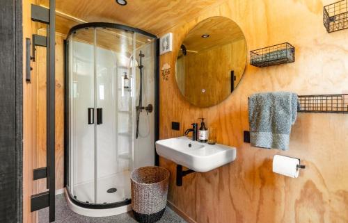 La salle de bains est pourvue d'un lavabo, d'une douche et d'un miroir. dans l'établissement Stylish hideaway on High st Carterton, à Carterton