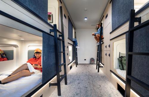 eine Person, die auf einem Bett im Zugraum sitzt in der Unterkunft LyLo Auckland in Auckland