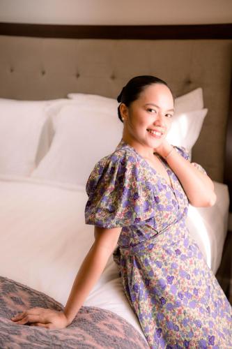 a woman in a dress sitting on a bed at Patio by Balai Norte in San Juan