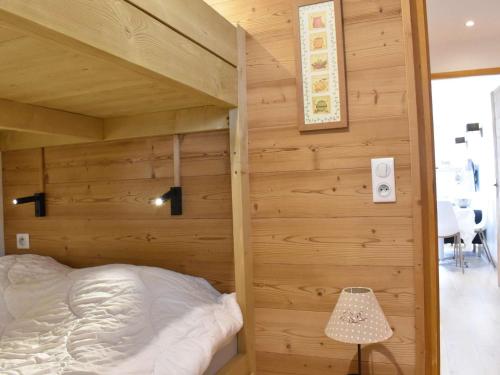 un lit dans une chambre avec un mur en bois dans l'établissement Charmant 2 pièces pour 4 à Méribel, à proximité des pistes, commerces et navette - FR-1-180-368, à Les Allues