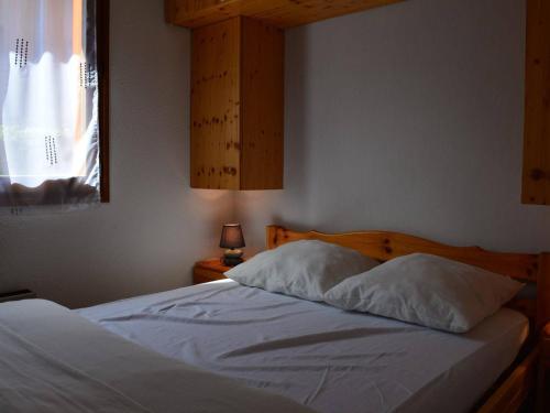 a bedroom with a bed with white sheets and a window at Appartement Le Grand-Bornand, 2 pièces, 6 personnes - FR-1-241-212 in Le Grand-Bornand