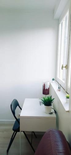 einen weißen Schreibtisch und einen Stuhl in einem Zimmer mit Fenstern in der Unterkunft Chez Erwan & Elizabeth in Rennes