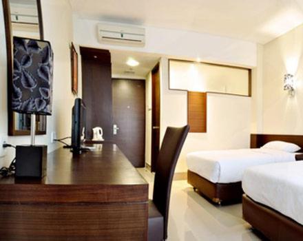 Habitación de hotel con cama, escritorio, cama y cama en BAMBOO INN HOTEL & CAFE, en Yakarta