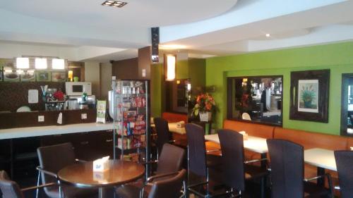 un restaurante con mesas, sillas y paredes verdes en BAMBOO INN HOTEL & CAFE, en Yakarta