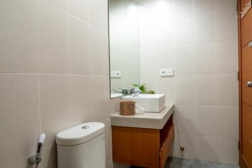 a bathroom with a toilet and a sink and a mirror at House of Michella - Modern, Quiet & Central in Sanur