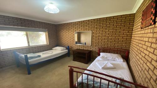 two beds in a room with a brick wall at Puggle Palace in Jurien Bay